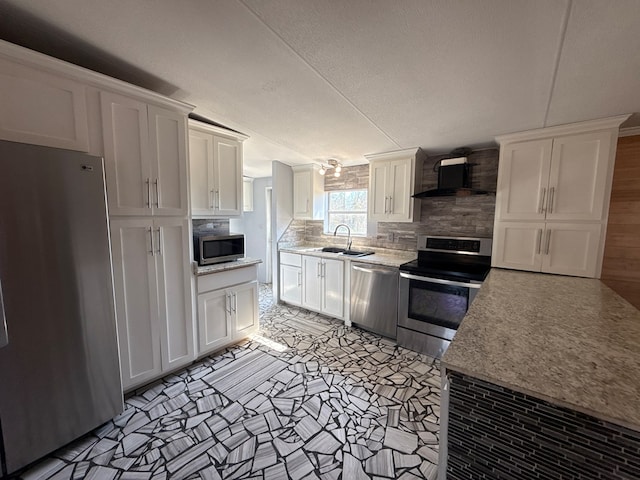 kitchen with wall chimney range hood, appliances with stainless steel finishes, and white cabinets