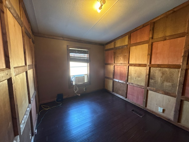 unfurnished bedroom featuring a textured ceiling, cooling unit, visible vents, vaulted ceiling, and dark wood finished floors