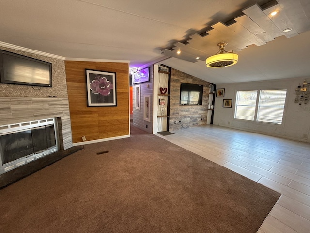 unfurnished living room with a fireplace, visible vents, carpet flooring, vaulted ceiling, and wood walls