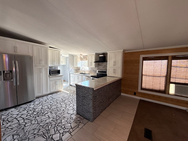 kitchen featuring stainless steel appliances, white cabinets, a sink, a peninsula, and wall chimney exhaust hood