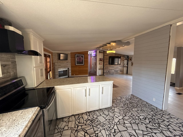 kitchen with range hood, open floor plan, electric stove, and a glass covered fireplace