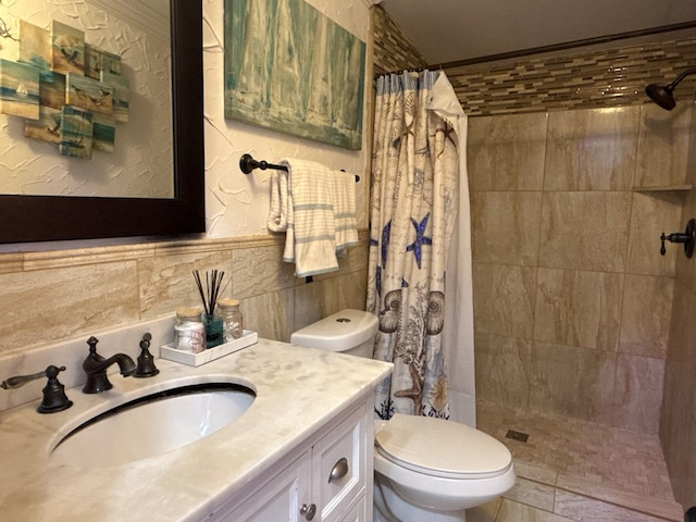 bathroom with tile walls, a tile shower, vanity, and toilet