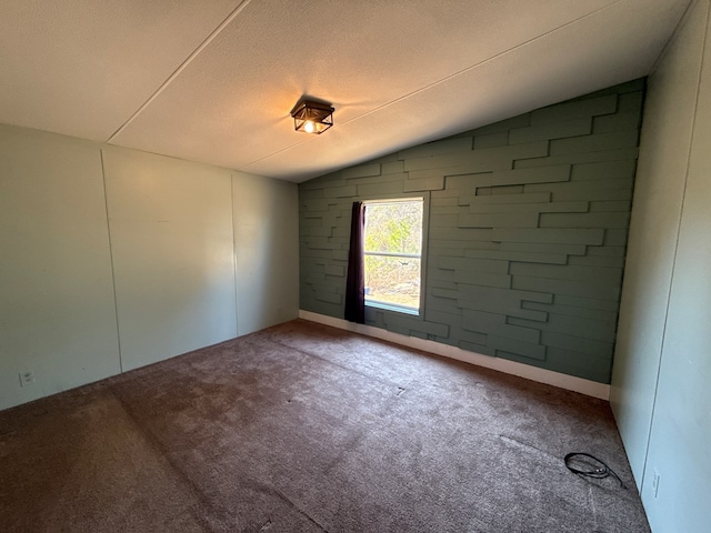 unfurnished room with lofted ceiling, a textured ceiling, and carpet flooring