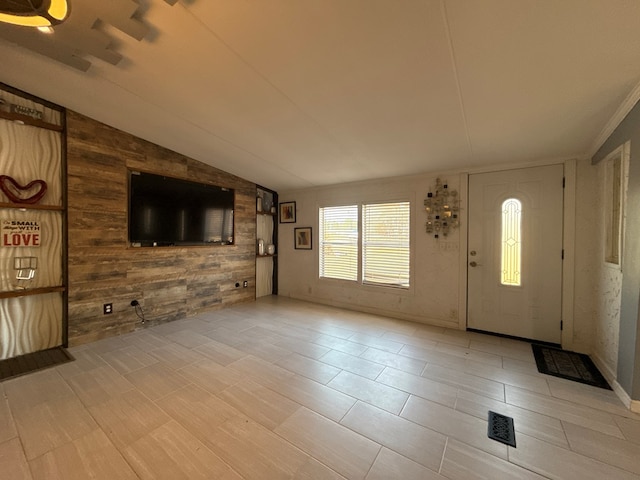 unfurnished living room with vaulted ceiling and wooden walls