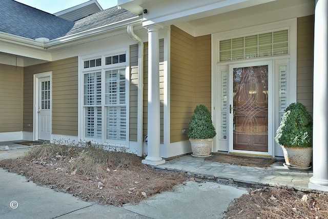 doorway to property with roof with shingles