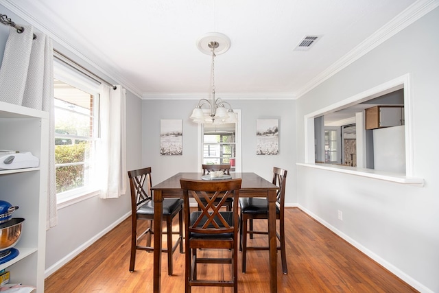 dining room with crown molding, hardwood / wood-style floors, and a chandelier