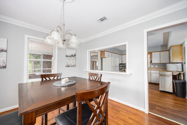 dining space with crown molding, light hardwood / wood-style flooring, and a chandelier