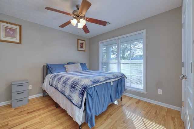 bedroom featuring a ceiling fan, baseboards, and light wood finished floors