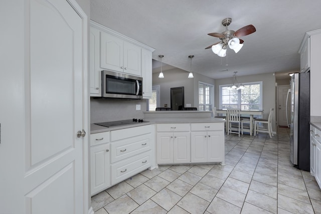 kitchen featuring ceiling fan with notable chandelier, appliances with stainless steel finishes, white cabinetry, and light countertops