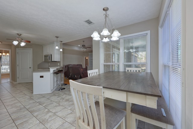 dining room featuring visible vents, ceiling fan with notable chandelier, a textured ceiling, and plenty of natural light