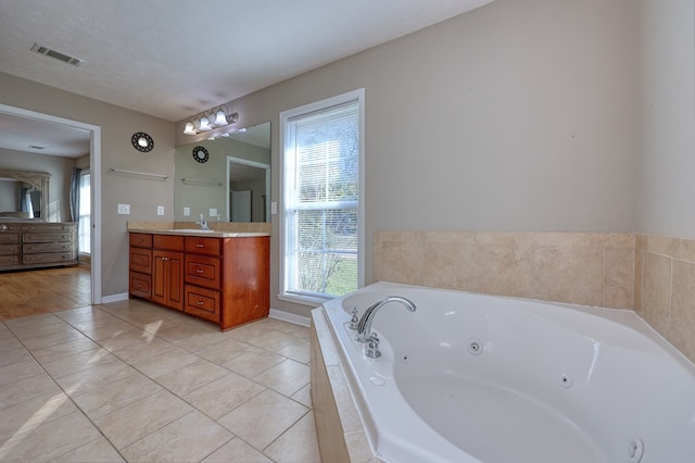 bathroom with vanity, visible vents, a textured ceiling, tile patterned floors, and a jetted tub