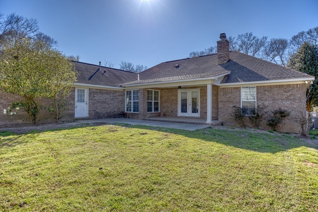 back of house with roof with shingles, a yard, a chimney, french doors, and a patio area