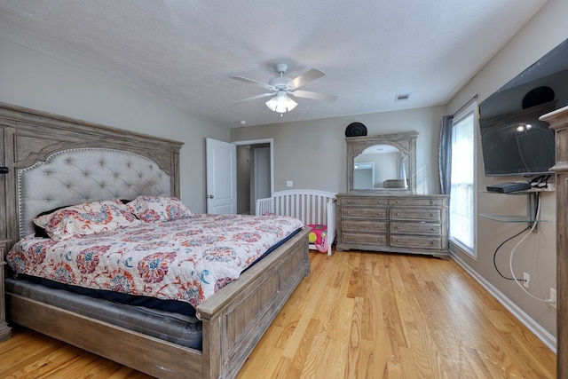 bedroom with visible vents, light wood-style flooring, a textured ceiling, and ceiling fan