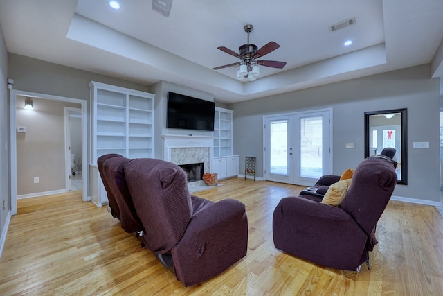 living area with visible vents, french doors, light wood-style floors, and a tray ceiling