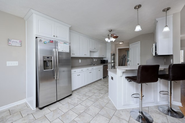 kitchen with stainless steel appliances, a peninsula, white cabinets, light countertops, and ceiling fan