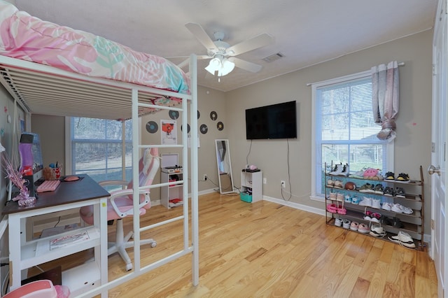 bedroom with ceiling fan, wood finished floors, visible vents, and baseboards