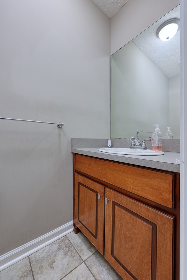 bathroom with vanity, baseboards, tile patterned flooring, and a textured ceiling