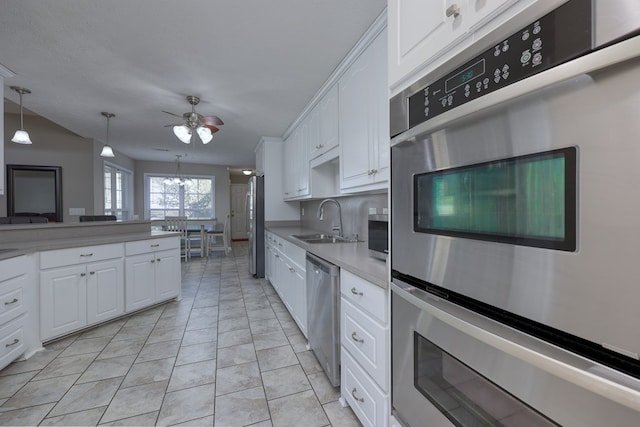 kitchen with white cabinets, ceiling fan with notable chandelier, stainless steel appliances, and a sink