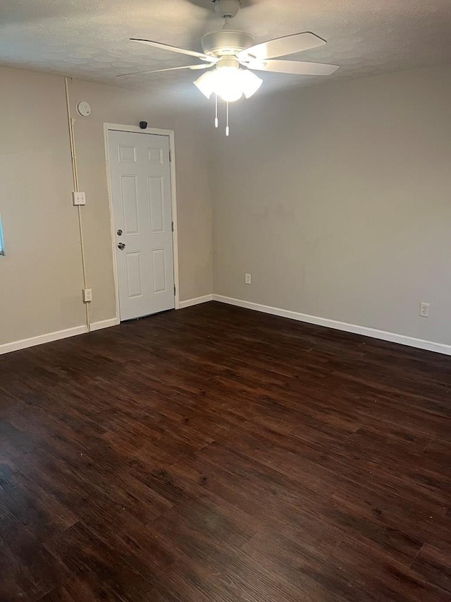 empty room featuring a textured ceiling, ceiling fan, and dark wood-type flooring