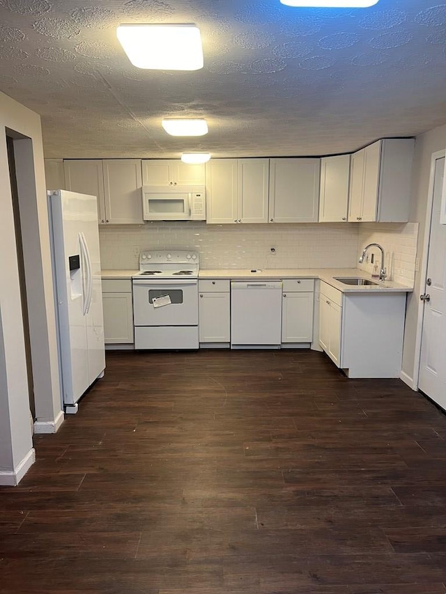 kitchen with dark hardwood / wood-style flooring, sink, white cabinets, and white appliances