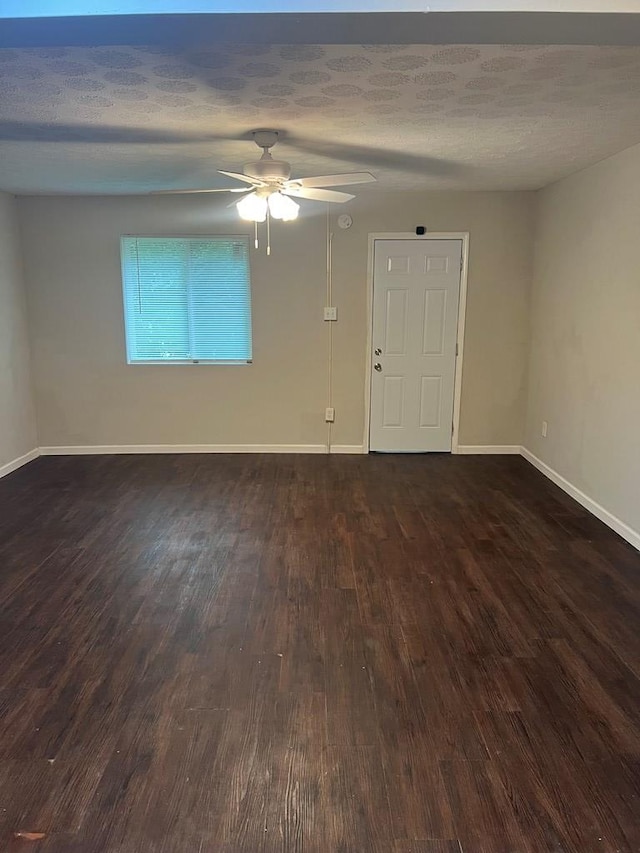 empty room with ceiling fan, dark hardwood / wood-style flooring, and a textured ceiling