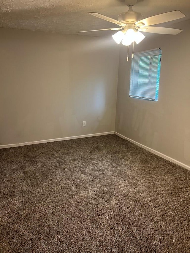 spare room with ceiling fan, dark carpet, and a textured ceiling