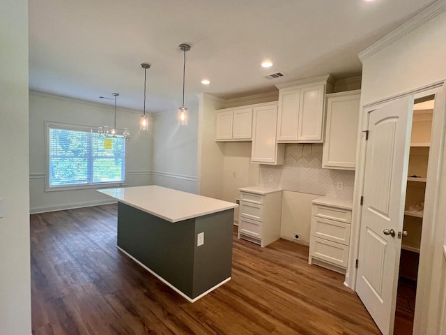 kitchen with dark hardwood / wood-style flooring, white cabinetry, a center island, and crown molding