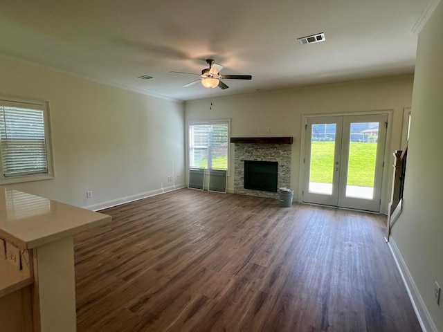 unfurnished living room with ornamental molding, dark hardwood / wood-style floors, a stone fireplace, and a wealth of natural light