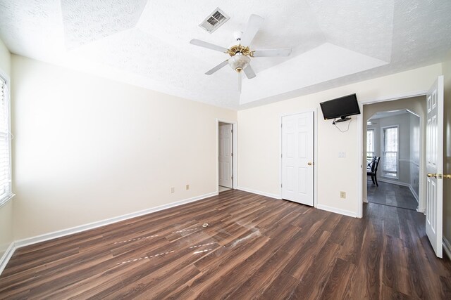 unfurnished bedroom featuring dark hardwood / wood-style floors, ceiling fan, a raised ceiling, and a textured ceiling