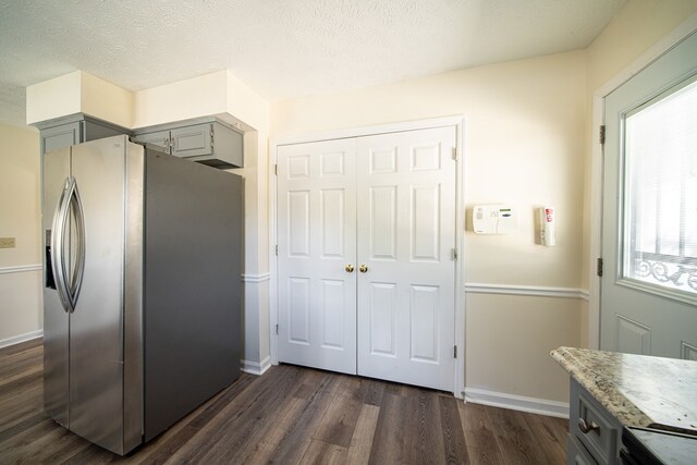 kitchen featuring stainless steel refrigerator with ice dispenser, a textured ceiling, gray cabinets, and dark wood-type flooring