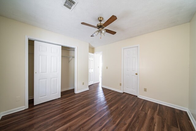 unfurnished bedroom with a textured ceiling, dark hardwood / wood-style floors, and ceiling fan