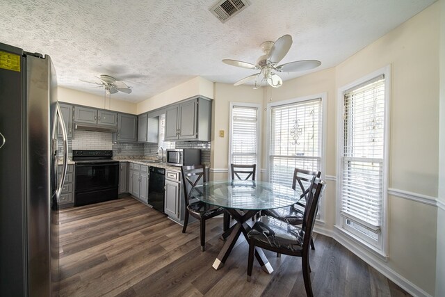 kitchen featuring ceiling fan, dark hardwood / wood-style floors, backsplash, gray cabinets, and black appliances