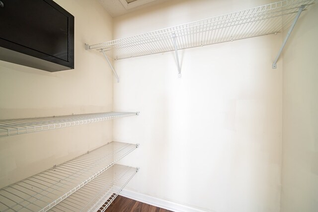 walk in closet with dark hardwood / wood-style flooring