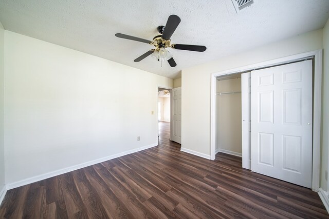 unfurnished bedroom with ceiling fan, a closet, dark wood-type flooring, and a textured ceiling