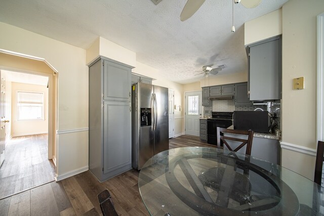 kitchen with gray cabinetry, black electric range, stainless steel fridge, tasteful backsplash, and a healthy amount of sunlight