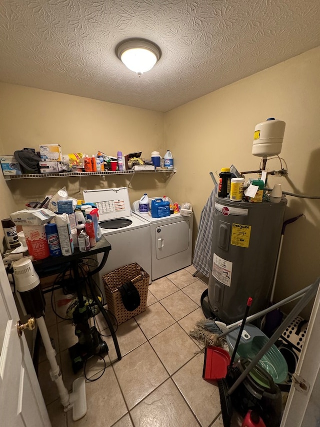 laundry area featuring washing machine and dryer, electric water heater, a textured ceiling, and light tile patterned floors