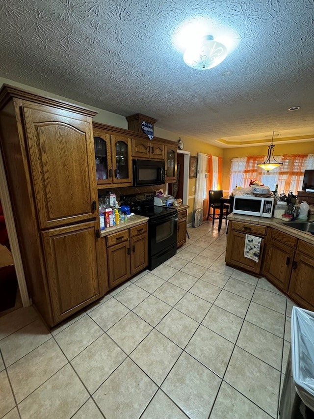 kitchen with black appliances, light tile patterned flooring, and a textured ceiling