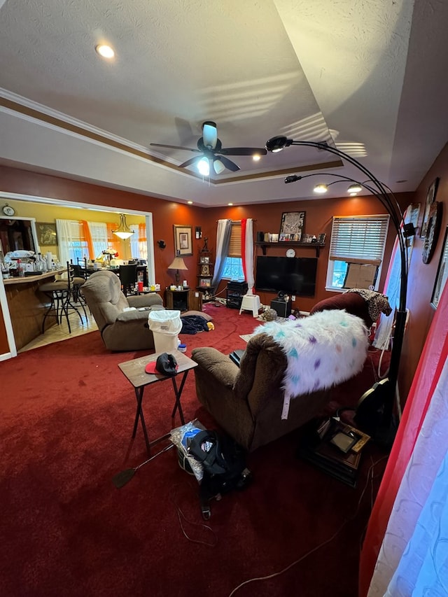 living room with carpet, ceiling fan, crown molding, and a textured ceiling