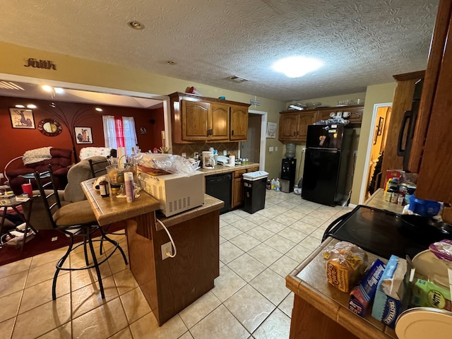 kitchen featuring kitchen peninsula, light tile patterned floors, a textured ceiling, and black appliances