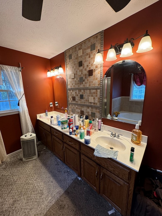 bathroom featuring plus walk in shower, a textured ceiling, vanity, and a wealth of natural light