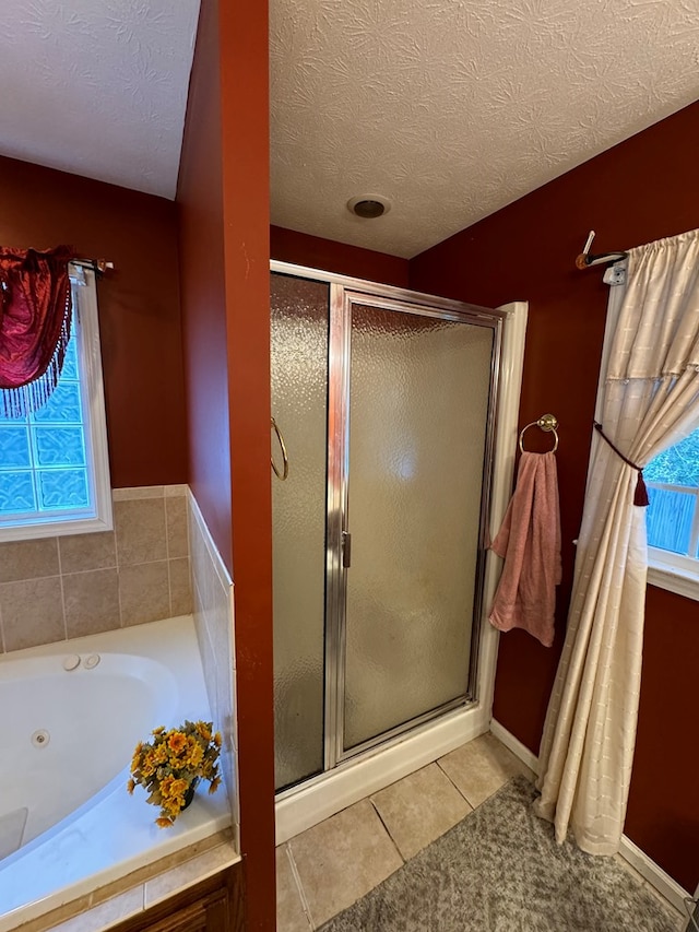 bathroom with plus walk in shower, a textured ceiling, and tile patterned floors