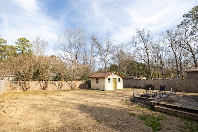 view of yard with an outbuilding, a storage shed, a fenced backyard, and a wooden deck