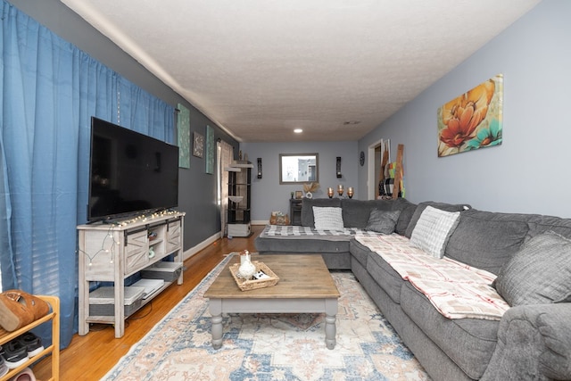 living area featuring a textured ceiling, light wood finished floors, and baseboards