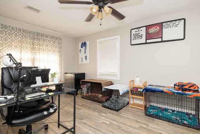 home office featuring a ceiling fan, visible vents, and wood finished floors