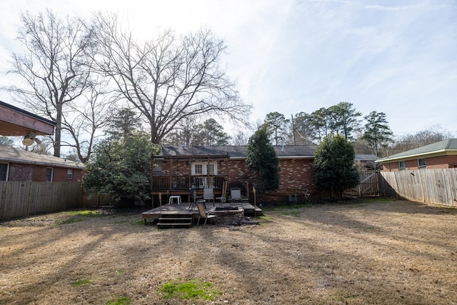 back of house with a yard, a fenced backyard, brick siding, and a wooden deck