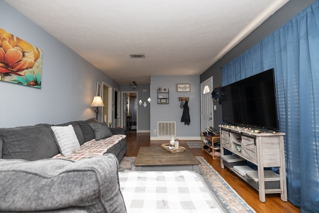 living area featuring baseboards, a textured ceiling, visible vents, and wood finished floors