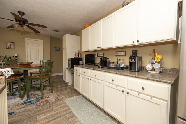 kitchen with visible vents, dark countertops, ceiling fan, a textured ceiling, and light wood-style floors