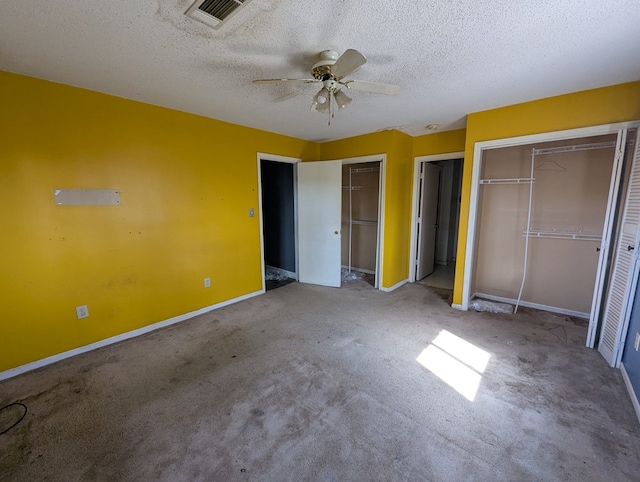 unfurnished bedroom featuring visible vents, two closets, carpet, baseboards, and a textured ceiling