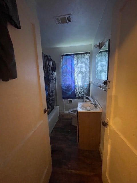 full bathroom with wood-type flooring, vanity, toilet, and shower / tub combo with curtain