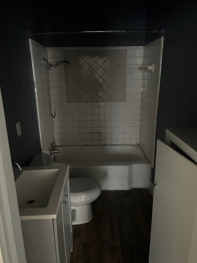 full bathroom featuring hardwood / wood-style floors, toilet, tiled shower / bath, and vanity